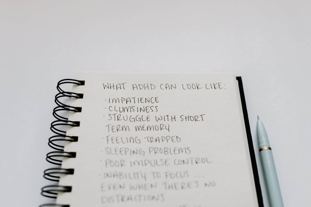 team-02 A notebook with handwritten ADHD symptoms like impatience and focus issues.